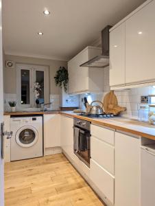 uma cozinha com armários brancos e uma máquina de lavar e secar roupa em 1BD apartment in Leyton zone 2 em Londres