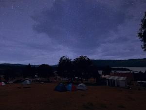 un grupo de tiendas de campaña en un campo bajo un cielo nocturno en Camping Las Acacias, en Guatavita