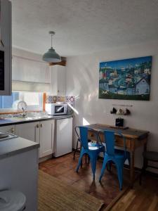 uma cozinha com uma mesa de madeira e cadeiras azuis em Bungalow 62,North Cornwall, St. Tudy em Saint Tudy