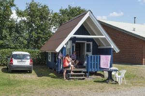 una pareja sentada fuera de una casita azul en Møgeltønder Camping & Cottages, en Møgeltønder