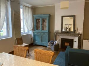 a living room with a blue cabinet and a fireplace at Le Logis de Pélagie in Neufchâtel-en-Bray