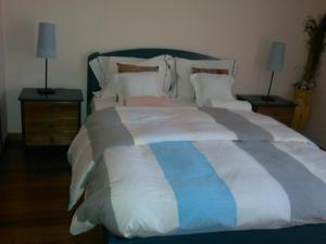 a bedroom with a large bed with white and blue sheets at Aguda Beachfront Apartment in Aguda