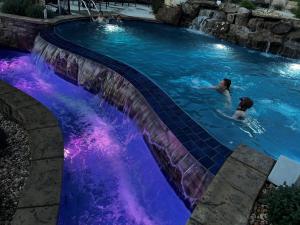 two people swimming in a pool with a waterfall at The Bavarian Village Resort in Branson
