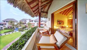 a room with a bed and a balcony with a view at Residences at Las Palmas in Zihuatanejo