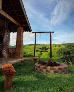 une terrasse couverte avec un banc et une balançoire dans l'établissement Chalés Encantos de Minas, à Bueno Brandão