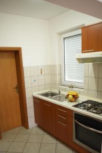 eine Küche mit einer Spüle, einem Herd und einem Fenster in der Unterkunft Apartmani MARIN in Županja