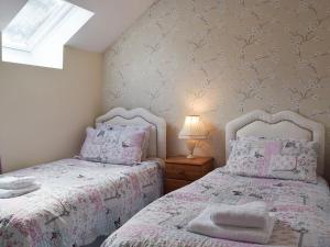 two beds in a bedroom with pink and white bedding at Upper Mill Barn in Nantgaredig