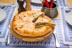 a pizza sitting on top of a wooden plate on a table at Ushguli Terrace in Ushguli
