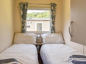 two beds in a small room with a window at Nice Cottage In Ilfracombe With 3 Bedrooms And Wifi in Ilfracombe