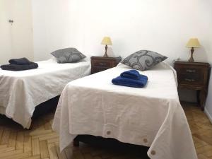 2 camas con sábanas blancas y toallas azules. en Departamento muy luminoso en el centro para 3 personas en Buenos Aires