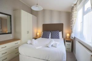 a bedroom with a white bed with two pillows at Devon Bliss Pool View Lodge at Finlake Resort in Chudleigh