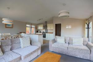 a living room with two couches and a kitchen at Devon Bliss - Pool View Lodge - Spa Resort in Devon in Chudleigh