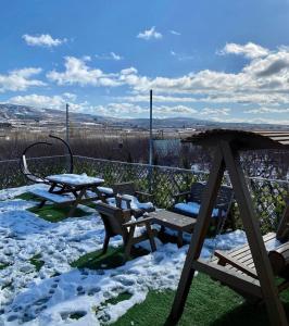 un patio cubierto de nieve con mesas de picnic y bancos en צימר המסה, en Mas'ada