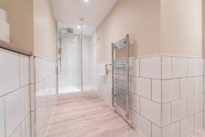 a bathroom with white tiled walls and a walk in shower at Stylish maisonette in town centre close to beach in Great Yarmouth