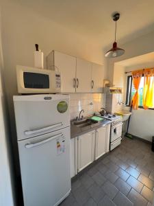 a kitchen with a microwave on top of a refrigerator at temporario la plata centro balcon al frente in La Plata