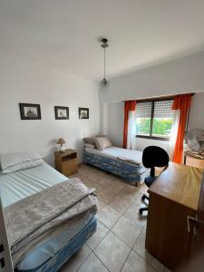 a bedroom with two beds and a desk and a chair at temporario la plata centro balcon al frente in La Plata