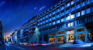 a building on a city street at night with cars at Hotel Cavour in Milan