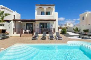 a villa with a swimming pool in front of a house at Villa Aguamarina in Playa Blanca