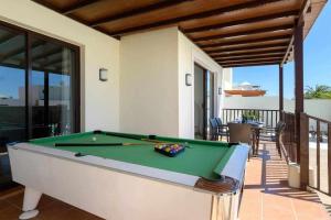 a pool table on a patio with a house at Villa Aguamarina in Playa Blanca