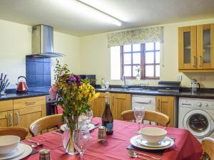 una cocina con una mesa con un jarrón de flores. en Merry, en Much Dewchurch