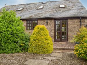 a brick house with a door and some bushes at Merry in Much Dewchurch