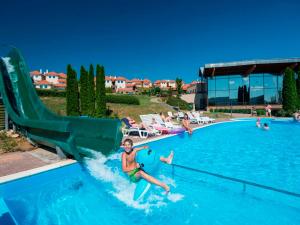 una mujer montando un tobogán de agua en una piscina en Landal Residence Duna, en Dunaszentmiklós