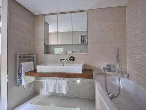 La salle de bains est pourvue d'un lavabo, d'une baignoire et d'un miroir. dans l'établissement The Apartments by The Sloane Club, à Londres