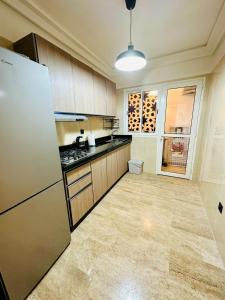 a large kitchen with a refrigerator and a window at Apartement sur la corniche, vue sur mer in Rabat