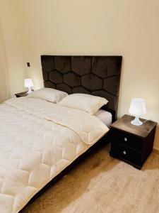 a bedroom with a large bed and a nightstand with two lamps at Apartement sur la corniche, vue sur mer in Rabat