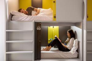mężczyzna i kobieta siedzący na łóżku piętrowym w obiekcie Free Hostels Roma w Rzymie