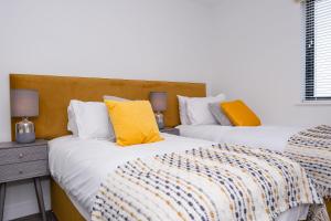 two beds in a room with yellow pillows at 4 Rockham - Luxury Apartment at Byron Woolacombe, only 4 minute walk to Woolacombe Beach! in Woolacombe