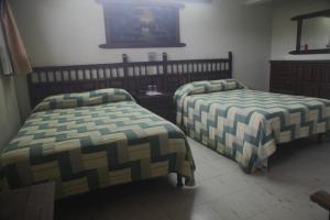 a bedroom with two beds and a tv on the wall at Hotel Iberia in Córdoba