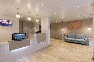 a waiting room with a couch and a tv in it at Hôtel de l'Étoile in Antibes