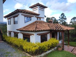 a house with a tiled roof and a tower at Caba-glamping La Fortuna de Luna in Villa de Leyva