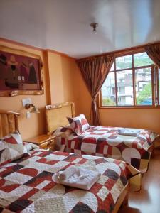 dos camas sentadas una al lado de la otra en un dormitorio en Hotel Santafe Inn, en Otavalo