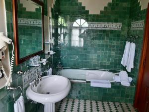 a green tiled bathroom with a sink and a tub at Hotel Castillo El Collado in Laguardia