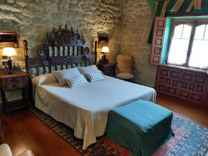 a bedroom with a large bed and a stone wall at Hotel Castillo El Collado in Laguardia