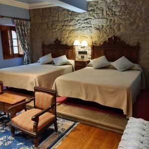 Un dormitorio con 2 camas y una silla. en Hotel Castillo El Collado, en Laguardia