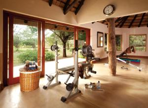 un gimnasio con cintas de correr y pesas en una habitación con ventanas en Kings Camp, en Reserva Timbavati