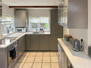 a large kitchen with gray cabinets and a window at The Causeway in Eyam