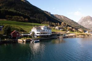 a large white house on the shore of a body of water at Fjærland Fjordstove Hotell - Huseby Hotelldrift AS in Fjarland