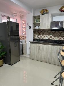een keuken met een zwarte koelkast en een wastafel bij Lindo Apartaestudio cerca al centro in Itagüí