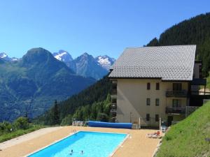 a swimming pool in front of a building with mountains at Appartement Auris, 2 pièces, 3 personnes - FR-1-297-299 in Auris