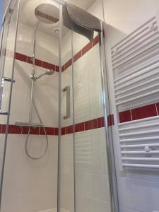 La salle de bains est pourvue d'une douche et de carrelage rouge et blanc. dans l'établissement Les Gîtes d'Angres - gîte n°1, à Angres