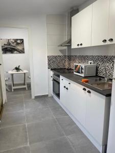 a kitchen with white cabinets and a sink and a table at Confortable adosado en Elche in Elche