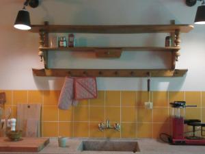 a kitchen with a sink and a shelf on the wall at Zintuinen in Esbeek