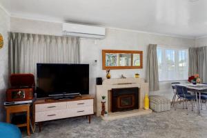 a living room with a television and a fireplace at Retro Cottage in Opotiki CBD in Opotiki