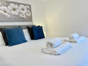 Una cama blanca con almohadas azules y toallas. en *Modern & Stylish 2 Double Bedroom-Free Parking!*, en Bristol