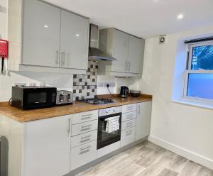 a kitchen with white cabinets and a black microwave at *Modern & Stylish 2 Double Bedroom-Free Parking!* in Bristol