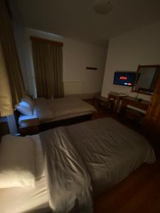 a hotel room with two beds and a flat screen tv at Ξενώνας Ράπτης 